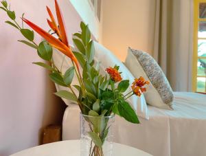 un jarrón con flores en una mesa junto a un sofá en Canto do Mar - Apartamentos e Casa com vista pro Mar - Cumuruxatiba en Cumuruxatiba
