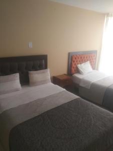ein Hotelzimmer mit 2 Betten und einem Fenster in der Unterkunft Hostal Chachani in Zamacola