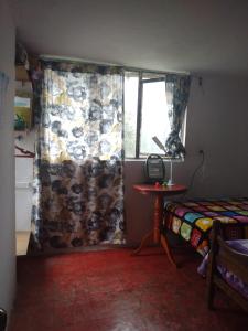 a bedroom with a window with a curtain and a table at Cálida habitación en casa hogareña. Ambiente familiar. in Teziutlán
