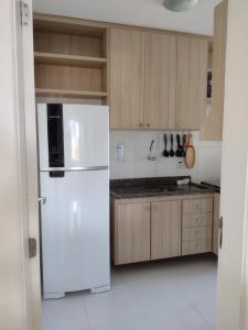 a white refrigerator in a kitchen with wooden cabinets at Apt Estrada do coco- Lauro de Freitas in Lauro de Freitas