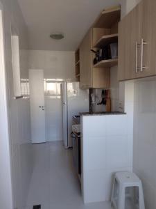 a kitchen with wooden cabinets and a white refrigerator at Apt Estrada do coco- Lauro de Freitas in Lauro de Freitas