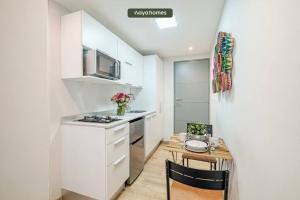 una cocina con armarios blancos y una mesa pequeña con sillas. en Great Apt in Polanco, en Ciudad de México