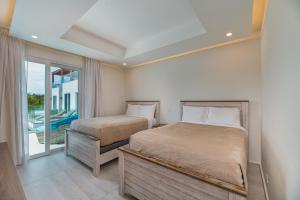 a bedroom with two beds and a balcony at Ocean One Roatan in West Bay