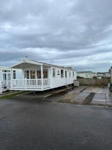 a white house with a porch on a parking lot at Luxurious 6 Berth Swift Bordeaux on Lyons Robin Hood Rhyl in Meliden