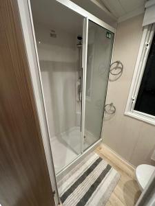 a glass shower in a bathroom with a toilet at Luxurious 6 Berth Swift Bordeaux on Lyons Robin Hood Rhyl in Meliden