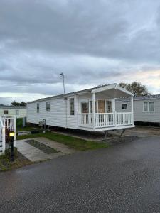 a white house with a porch on the side of it at Luxurious 6 Berth Swift Bordeaux on Lyons Robin Hood Rhyl in Meliden