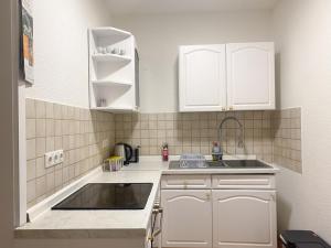una pequeña cocina con armarios blancos y fregadero en Accomodation in wuppertal, en Wuppertal
