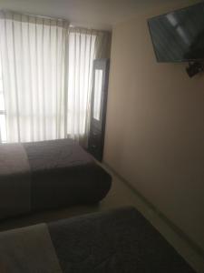 1 dormitorio con 1 cama y ventana con TV en Hostal Chachani, en Zamacola