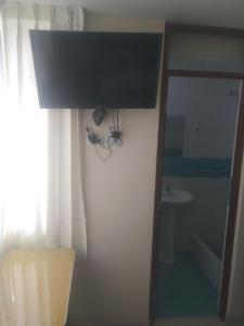 a bathroom with a sink and a television on a wall at Hostal Chachani in Zamacola