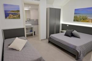 a bedroom with a bed and a bathroom with a sink at Altamarea Beach Experience Villetta LC in Marina di Pescoluse
