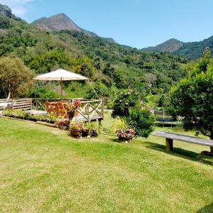 a park with a bench and an umbrella in the grass at Chalé Quinta Garden in Nova Friburgo