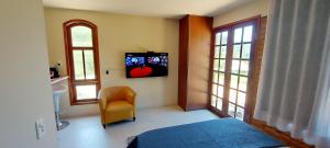 a bedroom with a bed and a chair and windows at Chalé do Riacho in Nova Friburgo