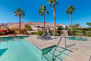 a swimming pool with two chairs and palm trees at Thai Palomino in Palm Springs