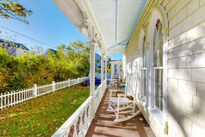 a porch of a white house with chairs on it at Victorian by the Sea in Oak Bluffs