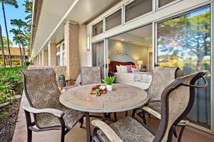 a patio with a table and chairs and a bed at Maui Kaanapali Villas A108 in Lahaina