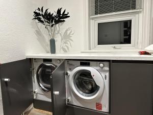 two washing machines in a laundry room with a counter at Heswall apartment in Wirral