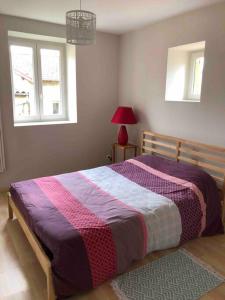 a bedroom with a bed with a purple and pink blanket at La Maison 1846  in Lentilly