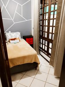 um pequeno quarto com uma cama e uma janela em Quarto privativo WC compartilhado em Joinville