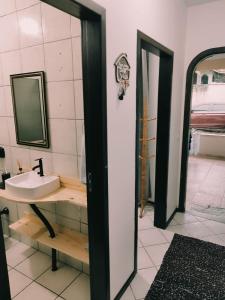 La salle de bains est pourvue d'un lavabo et d'un miroir. dans l'établissement Quarto privativo WC compartilhado, à Joinville