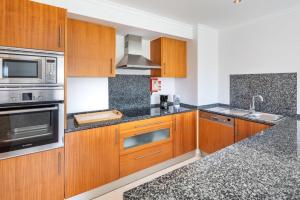 a kitchen with wooden cabinets and stainless steel appliances at Appartement Vista das ondas in Olhos de Água