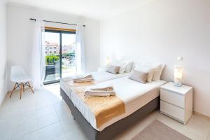 a white bedroom with a large bed and a window at Appartement Vista das ondas in Olhos de Água