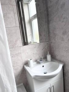 a white bathroom with a sink and a mirror at Awesome 4 Bed House in Manchester in Manchester