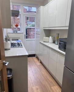 曼徹斯特的住宿－Awesome 4 Bed House in Manchester，厨房铺有木地板,配有白色橱柜。
