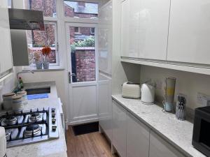 曼徹斯特的住宿－Awesome 4 Bed House in Manchester，白色的厨房配有炉灶和窗户。