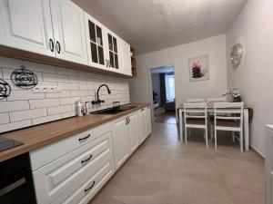 una cocina con armarios blancos y una mesa con sillas. en Izba “Jakub”, en Martin