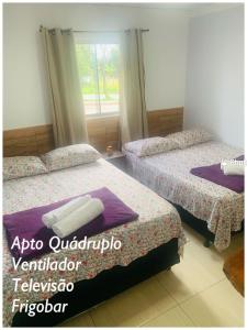two beds in a room with a window at Pousada Estrela Veadeiros in Alto Paraíso de Goiás