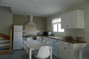 a kitchen with white cabinets and a table and chairs at Gite des Perrines 