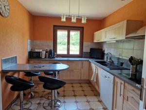 a kitchen with a table and bar stools in it at Maison 3 chambres in Commentry