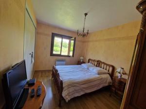 Schlafzimmer mit einem Bett, einem TV und einem Tisch in der Unterkunft Maison 3 chambres in Commentry