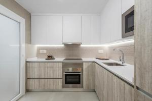 a kitchen with white cabinets and a sink at Casa Pajo - Moderna, personal y con bicicletas in San Pedro del Pinatar