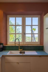 een keuken met een wastafel en 2 ramen bij Villa Paloma - nature meets design in Tourrettes-sur-Loup