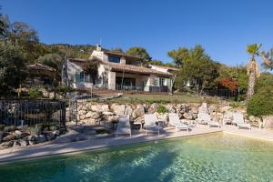 een huis met een zwembad met stoelen en een huis bij Villa Paloma - nature meets design in Tourrettes-sur-Loup