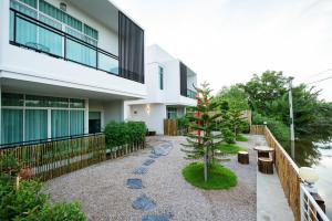 een tuin voor een gebouw met een boom bij Yunoya Riverside Villa in Samut Songkhram