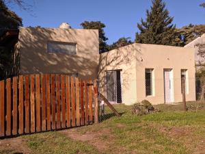 ein Zaun vor einem Haus mit einem Gebäude in der Unterkunft Casa Lidia in Chascomús