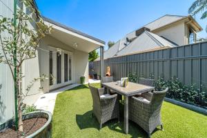 une petite cour arrière avec une table et des chaises sur l'herbe dans l'établissement Waratah Cottage 1910 - Boutique, à Glenunga