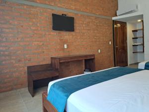 ein Schlafzimmer mit einem Bett und einem TV an einer Backsteinwand in der Unterkunft PUNTA COCO VILLAS BEACH in Cojimíes