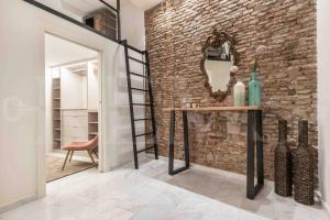 Habitación con pared de ladrillo, mesa y espejo. en Luxurious apartment in center with parking by REMS, en Málaga
