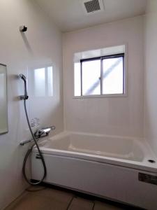 ein Bad mit einer Badewanne und einem Fenster in der Unterkunft Takachiho B&B Ukigumo in Takachiho