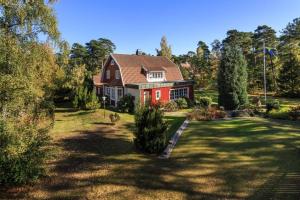 a red house with a red roof in a yard at Beach House Ängelholm in Ängelholm