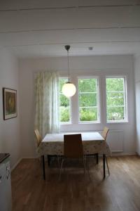 a dining room with a table and two windows at Beach House Ängelholm in Ängelholm
