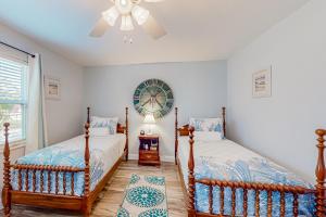 2 camas en un dormitorio con un reloj en la pared en The Harbour Home en Saint Augustine