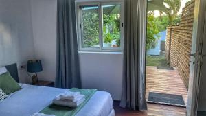 1 dormitorio con 1 cama, ventana y balcón en Bungalow cosy près des plages en Le Gosier