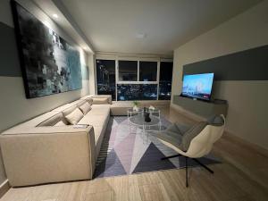 uma sala de estar com um sofá branco e uma televisão em Penhouse vista al mar y ciudad na Cidade do Panamá