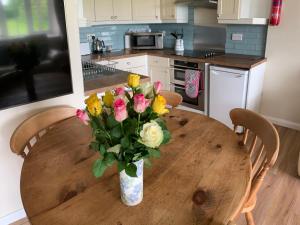 Primrose Cottage في مالتون: إناء من الزهور على طاولة خشبية في مطبخ