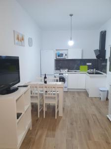 cocina con armarios blancos y mesa con TV en Casitas Isabelita, en Valle de Santa Inés