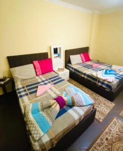 twee bedden in een kamer met roze en blauw bij Momen Pyramids Inn in Caïro
